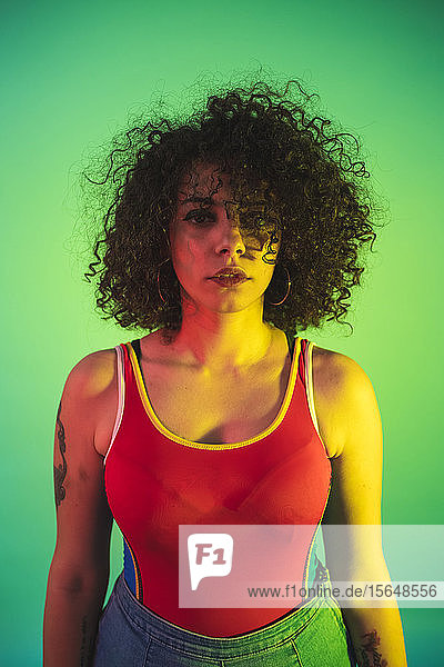 Young woman in red tank top posing against green background