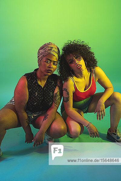 Young women squatting against green background