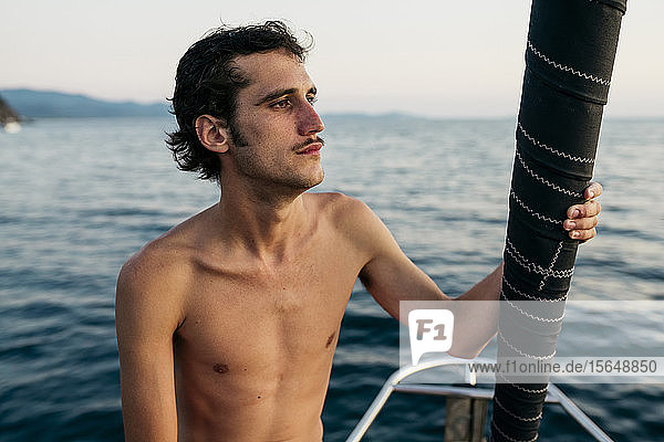 Junger Mann auf Segelboot schaut in die Ferne  Italien