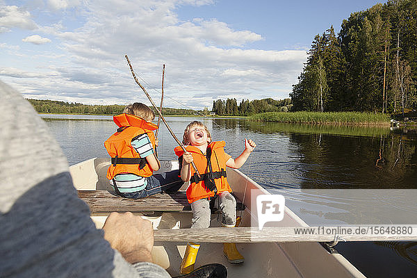 Erwachsener segelt mit aufgeregten Jungen auf einem Boot auf dem See  Finnland