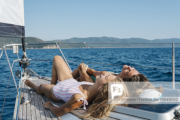 Freunde beim Sonnenbaden an Deck eines Segelbootes  Italien