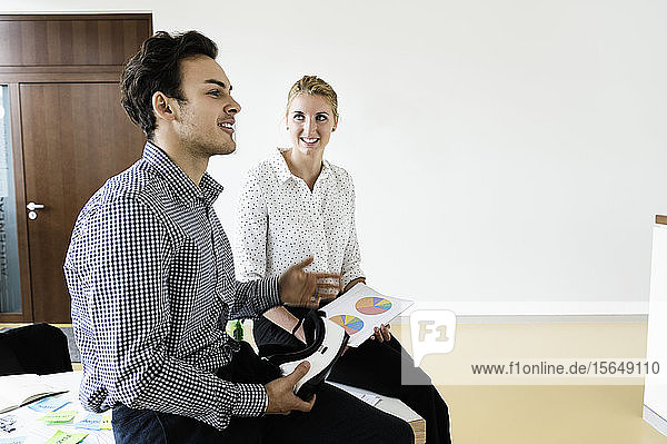 Geschäftsmann mit VR-Headset und Geschäftsfrau im Gespräch im Büro