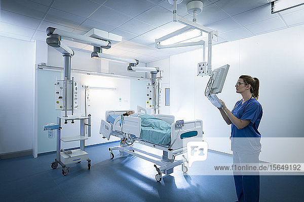 Nurse inspecting screen in intensive care unit in hospital setting