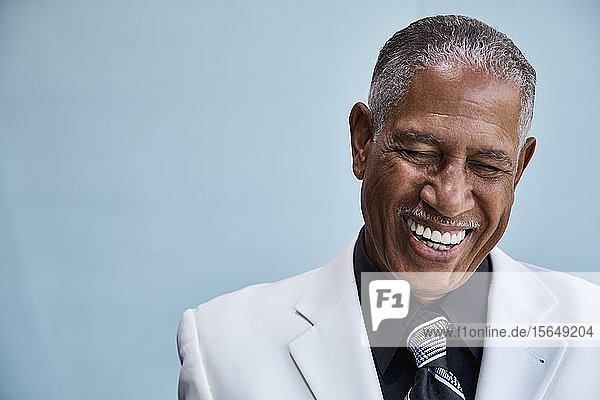 Portrait of senior businessman laughing  blue background