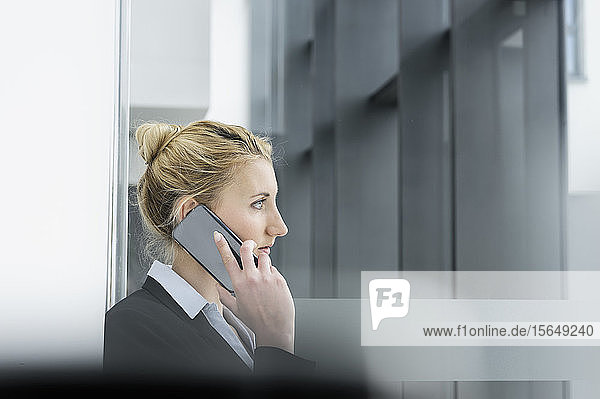 Junge Geschäftsfrau spricht mit einem Smartphone im Flur des Bürogebäudes