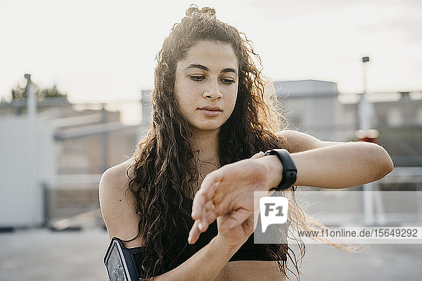 Young woman checking smartwatch on rooftop deck