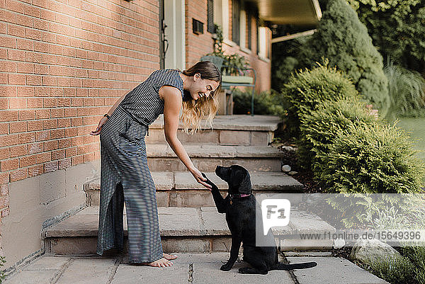 Frau schüttelt mit Hund die Pfoten