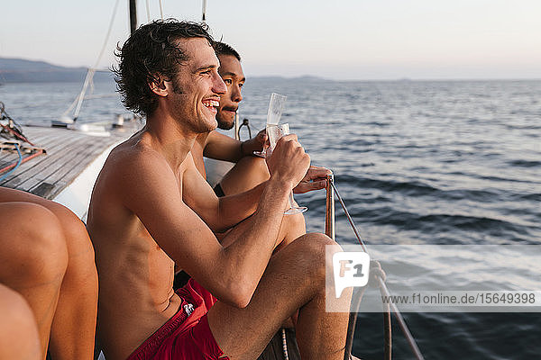 Junge Männer genießen Champagner auf einem Segelboot  Italien