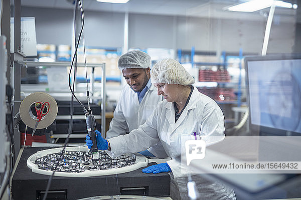 Workers assembling operating theatre lighting in electronics assembly factory