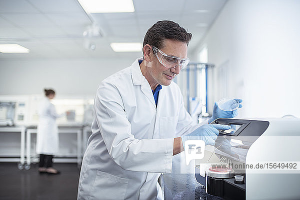 Scientist operating agar dish coating machine in laboratory