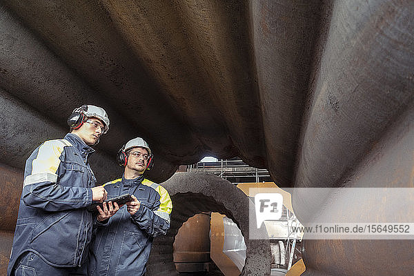 Arbeiter mit digitalem Tablett, das die Innenseite der Form in Stahlwerken inspiziert