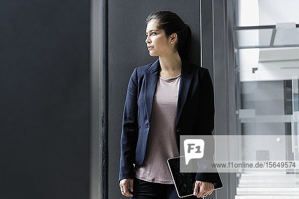 Junge Geschäftsfrau macht Pause im Korridor des Bürogebäudes