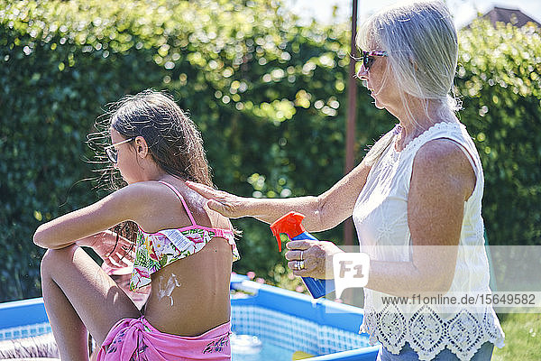 Großmutter cremt ihre Enkelin mit Sonnencreme ein