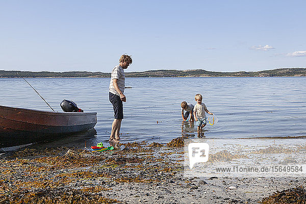 Father and sons playing beside boat moored on beach  Norway