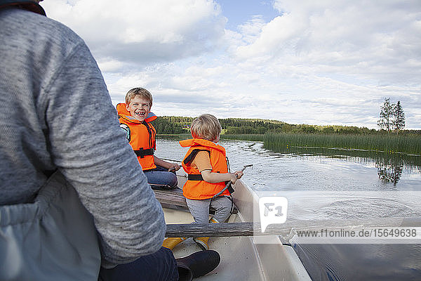 Erwachsener segelt mit Jungen auf einem Boot auf dem See  Finnland