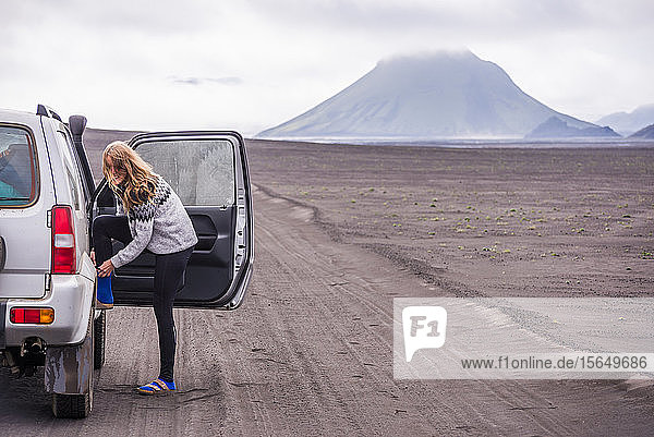 Frau beim Schuhwechsel an der Fahrzeugtür auf Feldweg Landmannalaugar Island