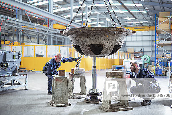 Engineers fitting spindle to pump parts in electrical engineering factory