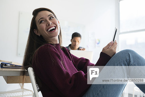 Lächelnde Frau mit Smartphone im Büro