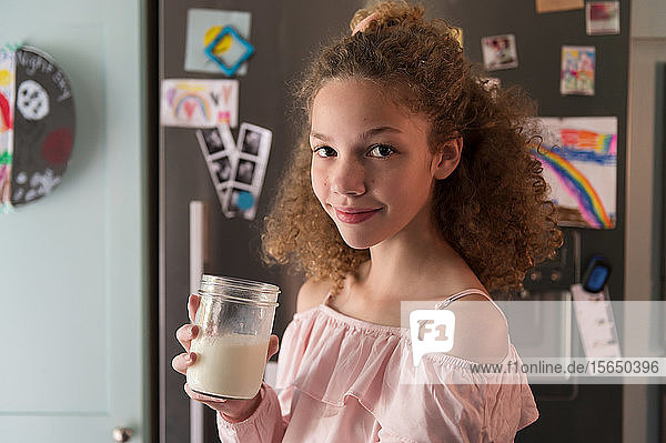 Mädchen hält ein Glas Milch in der Küche