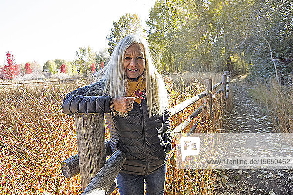 Woman holding leaf leaning on wooden fence in Bellevue  Idaho  USA