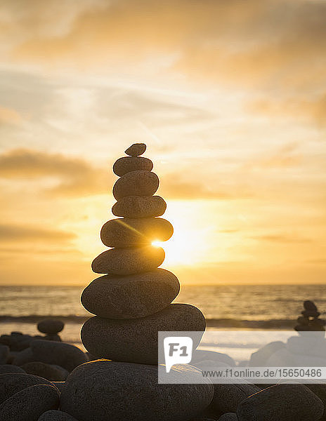 Gestapelte Steine am Strand bei Sonnenuntergang