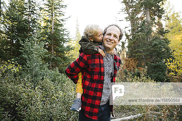 Vater und Sohn nehmen im Wald Huckepack