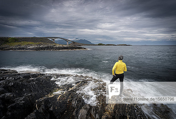 Wanderer  der die Atlantikstraße von den von den Wellen umspülten Klippen aus bewundert  Bezirk More og Romsdal  Norwegen  Skandinavien