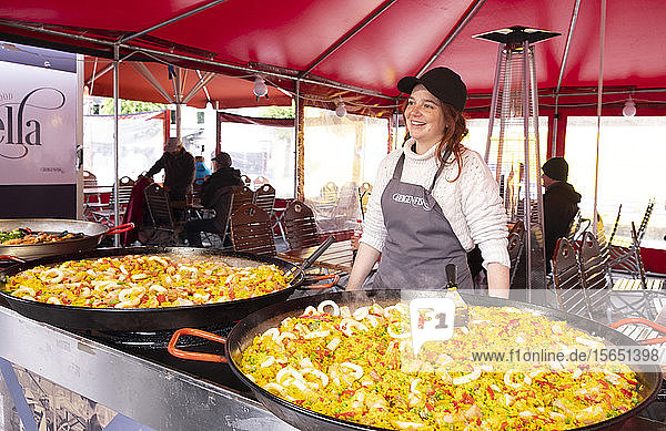 A smiling woman selling paella from huge pans in the fish market in Bryggen Bergen Norway Scandinavia Europe