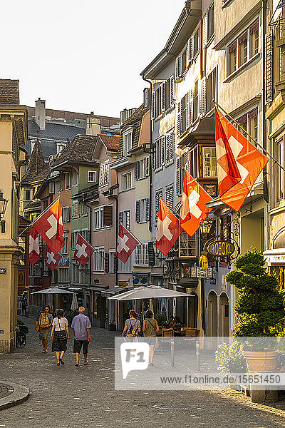 Touristen betrachten die Schweizer Fahnen  die an Gebäuden im Lindenhof hängen  Zürich  Schweiz  Europa