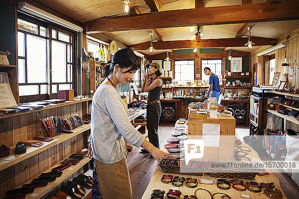 Zwei Japanerinnen und ein Japaner stehen in einem Ledergeschäft.