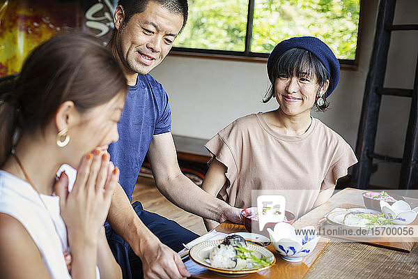 Waiter serving two Japanese women sitting at a table in a Japanese restaurant.