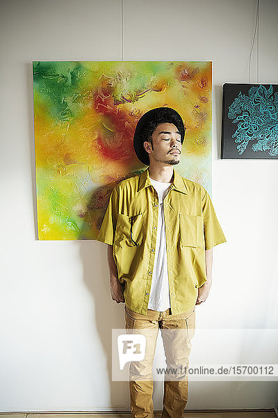 Japanischer Mann steht vor einem abstrakten Gemälde in einer Kunstgalerie.