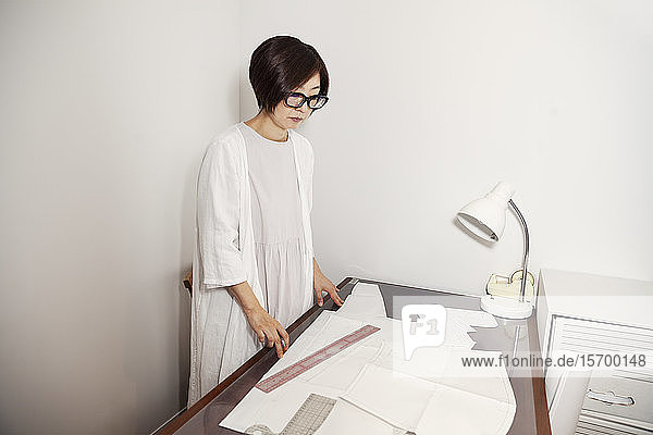 Brillenträgerin aus Japan  die in einer kleinen Modeboutique am Schreibtisch arbeitet.