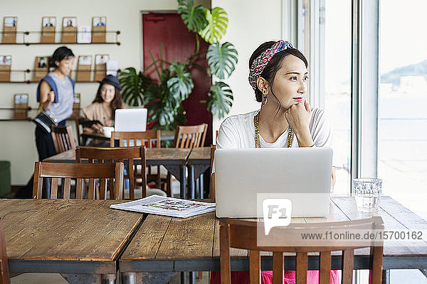 Group of young Japanese professionals working on laptop computers in a co-working space.