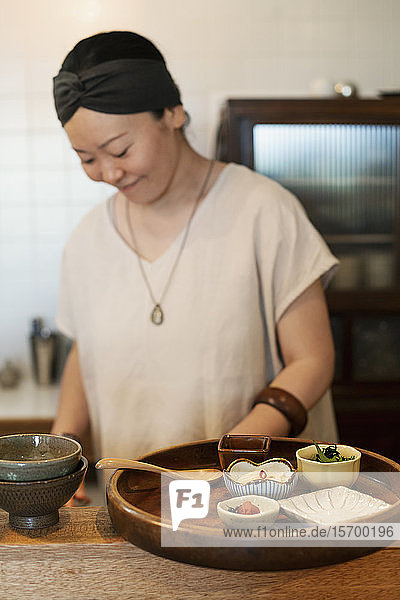 Japanerin  die in einem vegetarischen Café frisches Gemüse zubereitet.