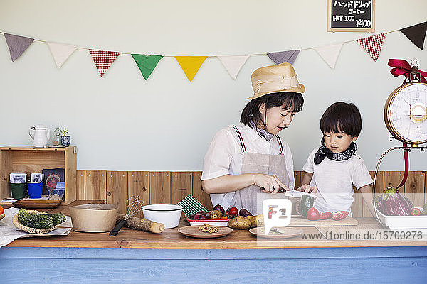 Japanische Frau und Junge stehen in einem Hofladen und bereiten Essen vor.