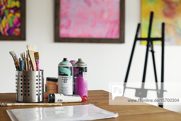 Innenansicht oder Kunstgalerie mit Atelierraum  Staffeleien und Dosen mit Sprühfarbe auf einem Tisch.