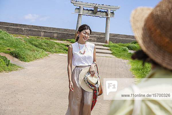 Zwei Japanerinnen mit Hüten stehen auf einem Weg und fotografieren.