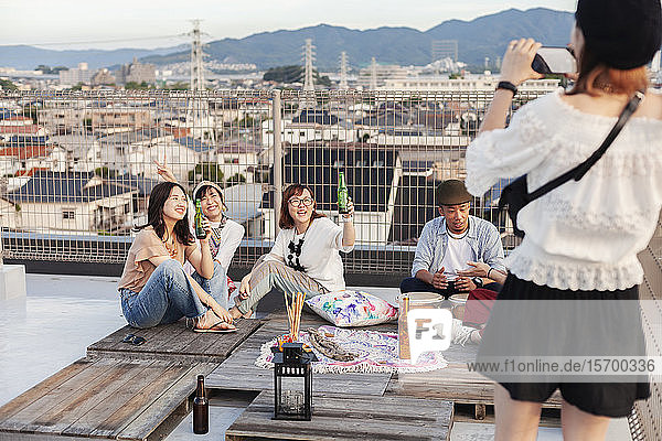Lächelnde Gruppe junger japanischer Männer und Frauen auf einem Dach in einer städtischen Umgebung.
