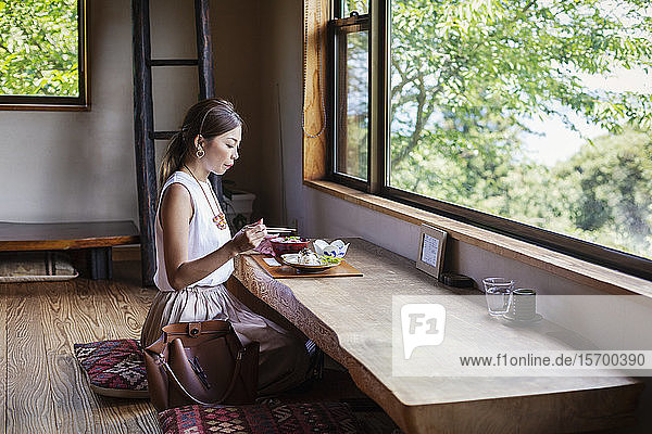 Japanerin  die an einem Tisch in einem japanischen Restaurant sitzt und isst.