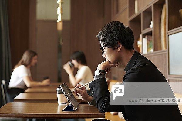 Junger japanischer Geschäftsmann in einem Cafe