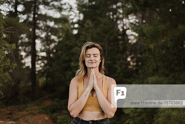 Frau praktiziert Yoga im Wald