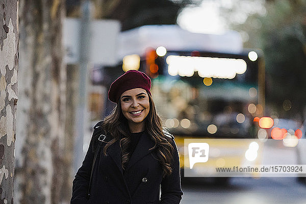 Porträt selbstbewusste junge Frau mit Baskenmütze auf städtischem Bürgersteig