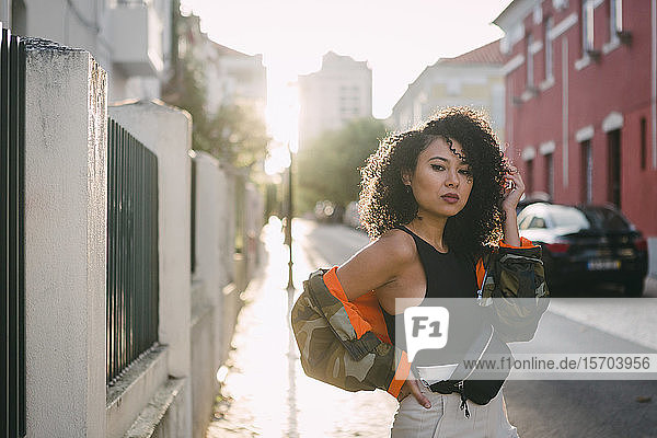Porträt einer selbstbewussten  stilvollen jungen Frau auf einer sonnigen Straße in der Stadt