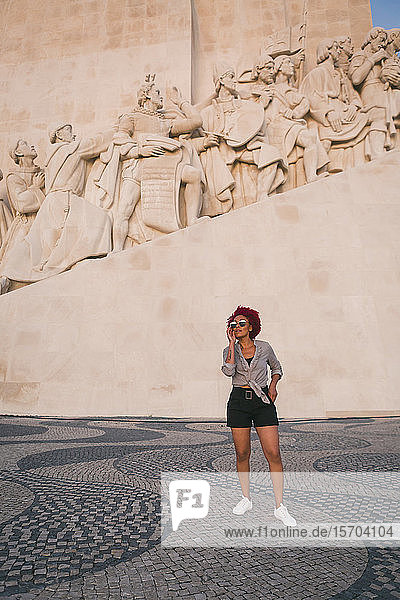 Stylish woman in sunglasses below Monument to the Discoveries, Lisbon, Portugal