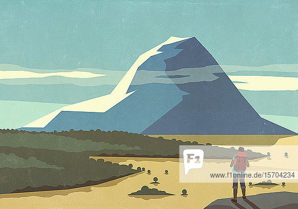Männlicher Rucksacktourist genießt die sonnige Aussicht auf eine malerische Berglandschaft