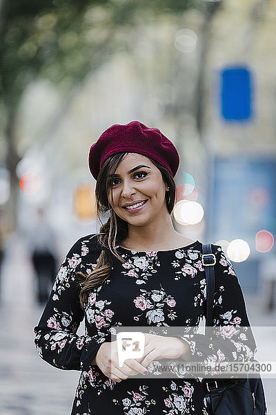 Porträt einer selbstbewussten  lächelnden jungen Frau mit Baskenmütze und geblümtem Kleid