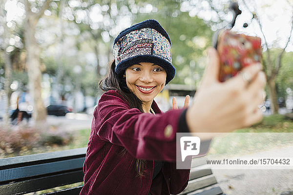 Glückliche Frau nimmt Selfie mit Kamera-Handy auf Parkbank