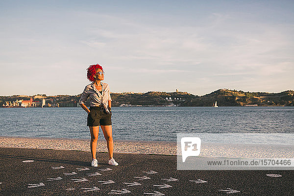 Portrait stylish woman standing at sunny waterfront  Tagus River  Portugal