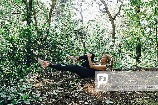 Fit weibliche persönliche Trainer Übung,  Stretching Beine im Wald